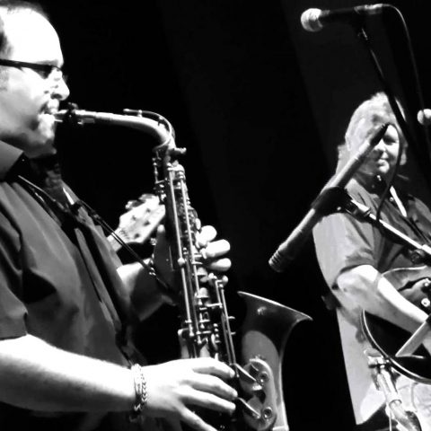 Black and white photo of Chris Beebe Aldridge playing sax with Climax Blues Band
